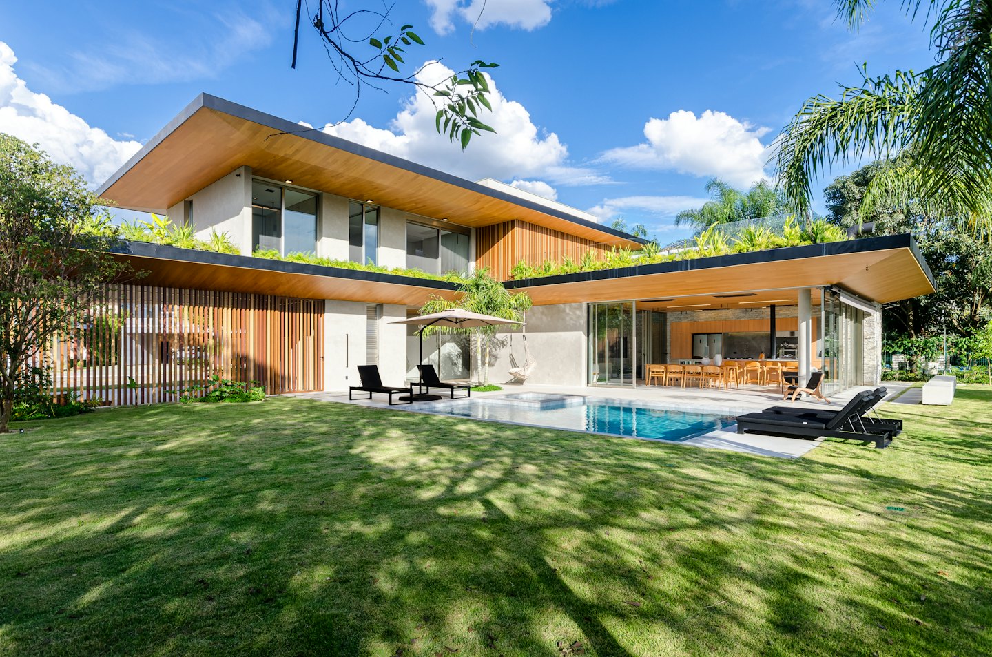 Modern house with green roof, lawn, and swimming pool.